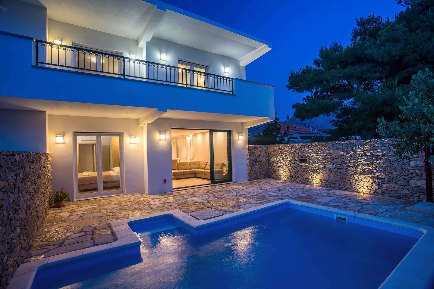 Villa exterior at night with lit pool and balcony