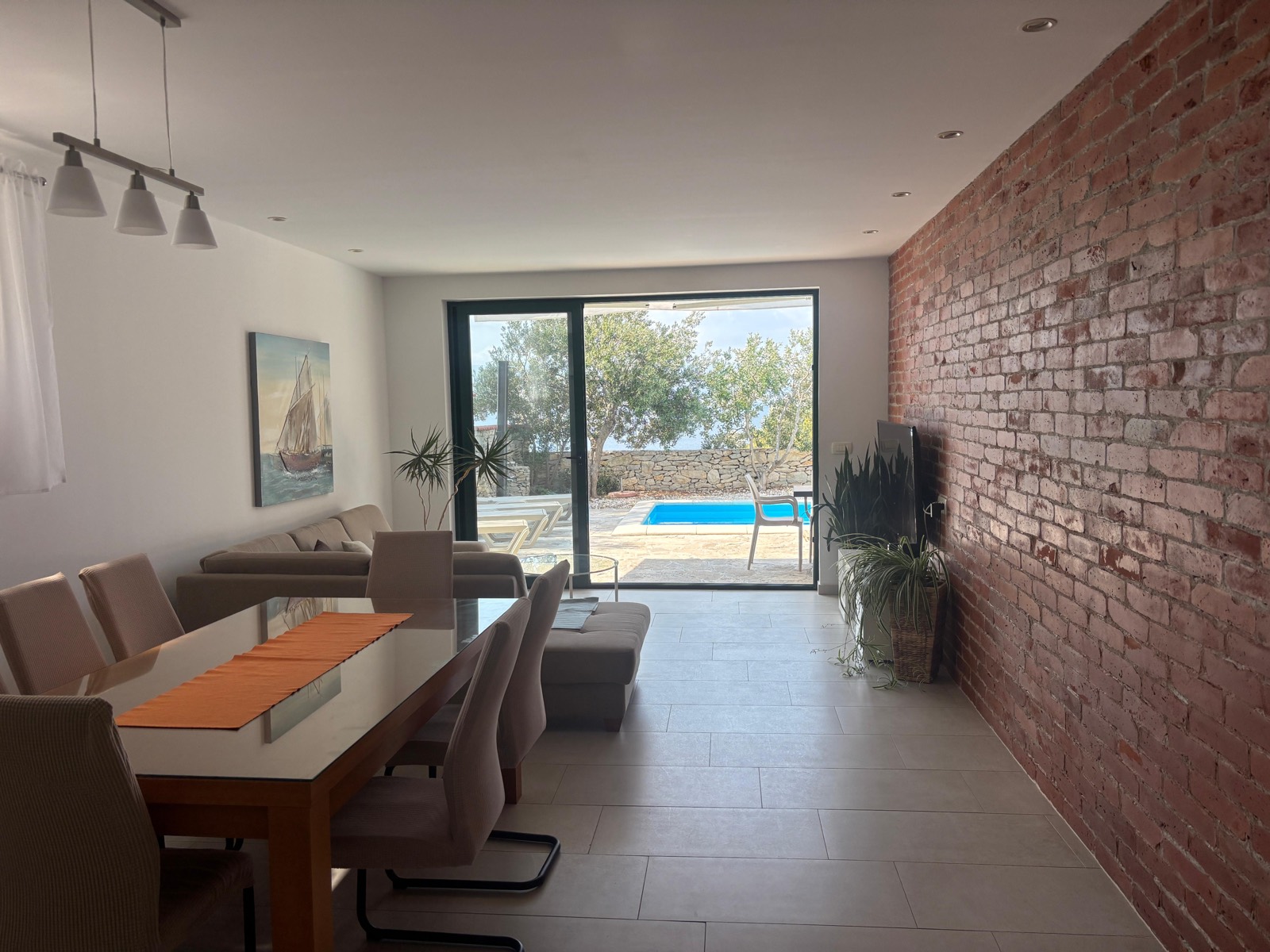 Living and dining area with new glass dining table, opening onto the pool